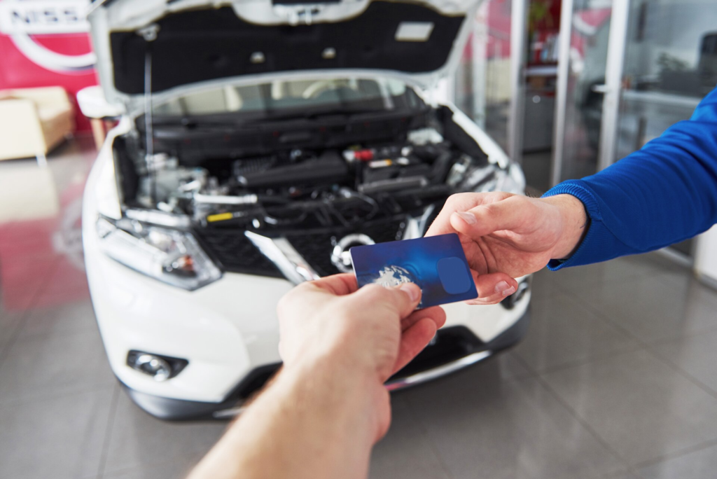 Hands of car mechanic with wrench in garage payment by credit card